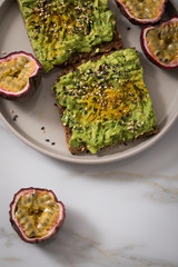 Avocado Kurkuma Vollkorn Sonnenblumenkern Brot und Maracuja zum Frühstück auf Marmor Hintergrund