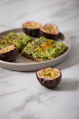 Avocado Kurkuma Vollkorn Sonnenblumenkern Brot und Maracuja zum Frühstück auf Marmor Hintergrund