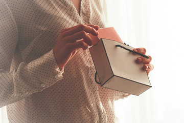 Stylish woman in a blouse pulling a box of favorite perfumes out of a gift paper bag. Fashion, beauty and style