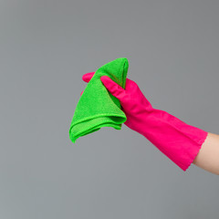 A hand in a rubber glove holds a bright microfiber duster on a neutral background. Сoncept of bright spring, spring cleaning.