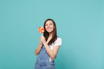 Portrait of pensive smiling young woman in denim clothes looking up, holding colorful round...