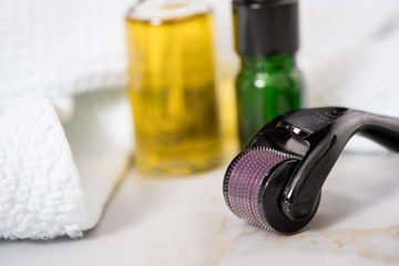 Dermaroller, Handtuch, gelbe Pflege Öl und grüne Serum Flaschen zum  Microneedling für Anti...