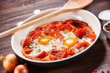 Shakshuka - fried eggs with vegetables in frying pan