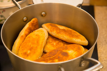 hot ruddy appetizing homemade pies in a saucepan on the stove. Kitchen