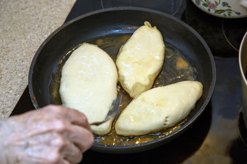 Female hand turns hot cakes in a pan with a fork. Kitchen