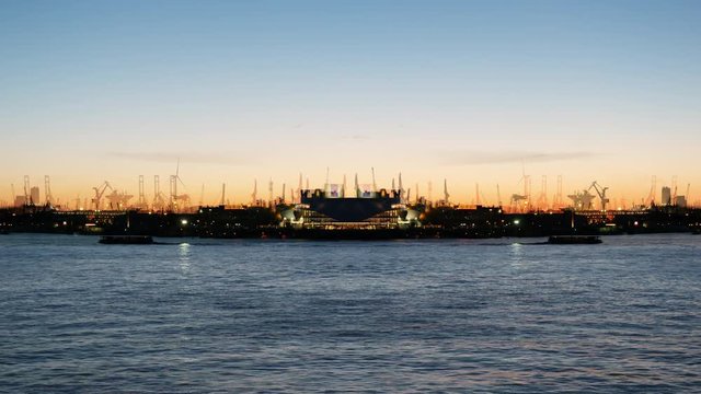 Digital composite footage of Stage Theater im Hafen at dusk with spectacle Mary Poppins and industrial pipes gas and oil factories in background