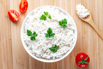 Bowl with white boiled rice with green fresh parsley and ripe tomatoes cherry for delicious healthy lunch. Cereal food and dishes. Top view