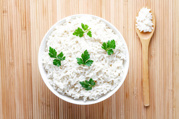 Bowl with white boiled rice with green fresh parsley for delicious healthy lunch. Cereal food and dishes. Top view