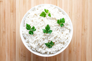 Bowl with white boiled rice with green fresh parsley for delicious healthy lunch. Cereal food and dishes. Top view