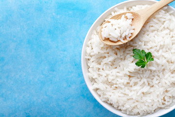 Bowl with boiled rice with green fresh parsley for delicious healthy lunch on a blue background. Cereal food and dishes. Top view and copy space