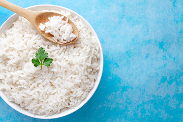 Bowl with boiled rice with green fresh parsley for delicious healthy lunch on a blue background. Cereal food and dishes. Top view and copy space