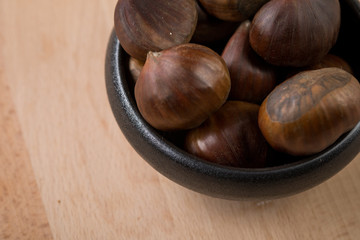 Maronen Esskastanien in schwarzer Schale auf Holz Hintergrund 