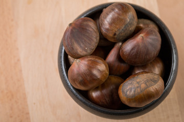 Maronen Esskastanien in schwarzer Schale auf Holz Hintergrund 