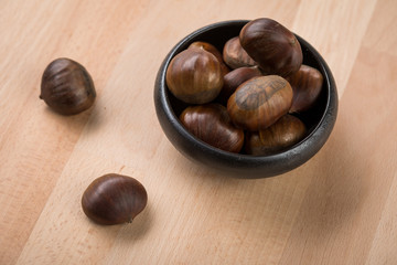 Maronen Esskastanien in schwarzer Schale auf Holz Hintergrund 