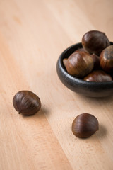 Maronen Esskastanien in schwarzer Schale auf Holz Hintergrund 