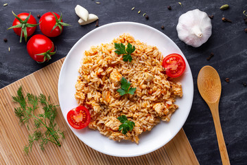Plate of homemade delicious pilaf with chicken, fresh parsley and ripe vegetables for lunch. Top...