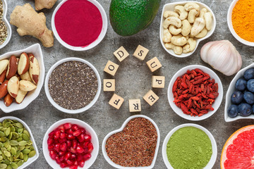 various superfoods on gray background. matcha, acai, turmeric, fruits, berries, avocado, mushrooms, nuts and seeds