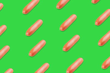 Diagonal rows of prepared long sausages on green background
