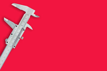 One metal vernier caliper on red table with copy space for your text. Top view. Industrial concept