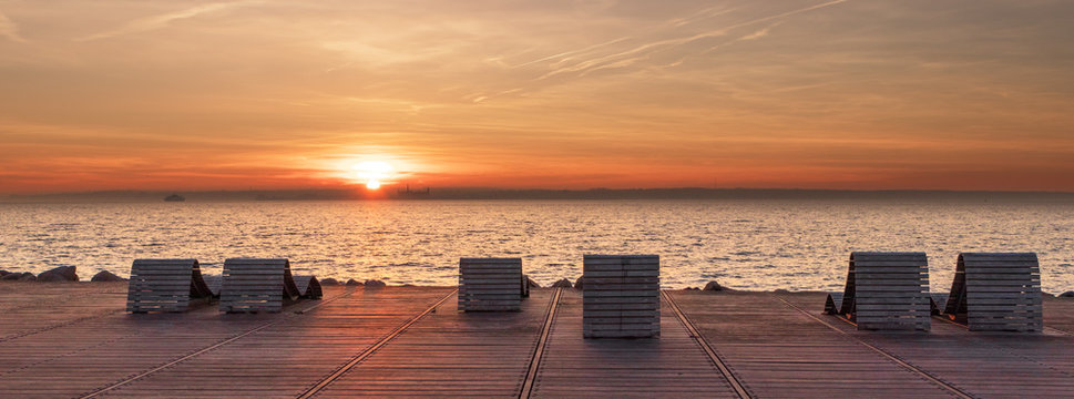 Sun beds at sunset with a view over the ocean Oresund between Denmark and Sweden. Castle Kronborg visible in the distance. View from the Swedish side in the city of Helsingborg. 