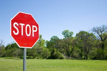 Stop Sign With Green Field And Trees - obrazy, fototapety, plakaty