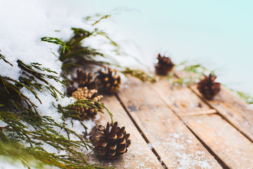 Christmas decor. Fir cones and  juniper branches on a wooden background. Snow still life. Winter.