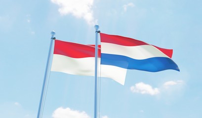 Netherlands and Indonesia, two flags waving against blue sky. 3d image
