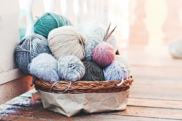 Fototapeta na wymiar Womens hobby. Skeins of yarn and knitting needles in the basket on wooden background.