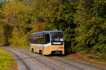 Fototapeta na wymiar Tram rides through the autumn park