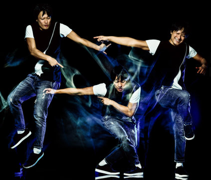 one chinese young man hip hop break dancer dancing isolated on black background with speed light painting effect motion blur