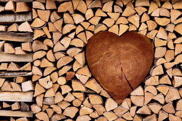 Firewood, nicely assembled in the shape of heart, romantic background, wooden texture, nature...