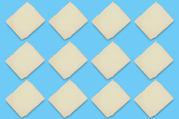 Rows of bricks of fat butter or margarine on blue table on kitchen. Top view. Seamless pattern