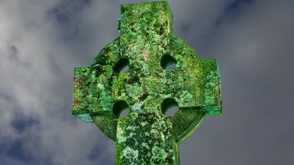 Colourful lichen covered Celtic Cross with fast motion clouds in a blue sky behind.