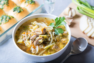 Shchi (cabbage soup) with buns (pampushki), fat and garlic. Traditional Russian and Ukrainian soup. Selective focus, close-up.