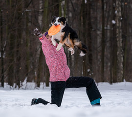 girl playing frisbee in the snow with a border collie dog