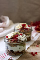 Granola with yogurt and fruit in glass jars on a wooden table. Rustic style.
