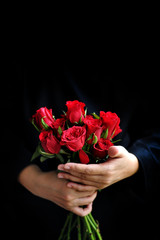 Woman hand holding a bouquet og fresh red roses