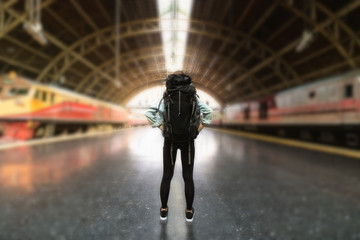 Back view of young Asian backpacker female standing at train station. Travel lifestyle concept.