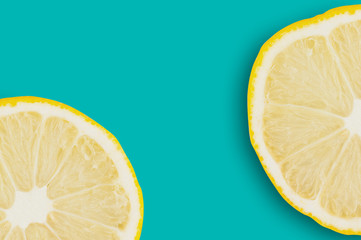 Two round pieces of fresh ripe sliced lemons on green table on cuisine. Copy space for your text....