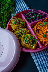 Italian food. Fetuchini pasta with minced meat, decorated with greens. Salad of carrots and cabbage. Rimmed break. Dark background. Side view.