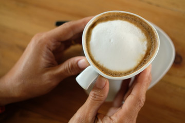 hand holidng latte cappuccino coffee cup
