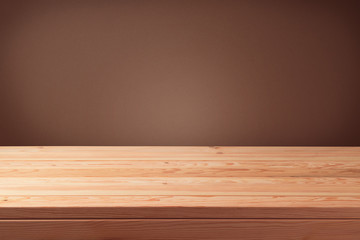 Empty wooden table over brown wall background.