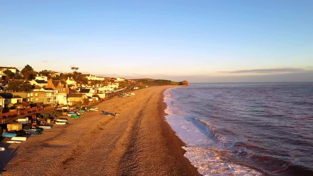 Aerial depiction of waves crashing on to the pebbled beach at the Devonshire seaside town of Budleigh Salterton. A popular Jurassic coastal destination for tourists and known for its literary festival