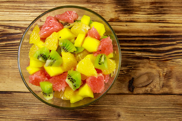 Tasty fruit salad in glass bowl on the wooden table