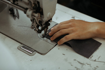 Sewing process of the leather wallet. Man's hands behind sewing. Leather workshop.