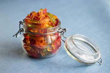 Chewing marmalade in the form of worms in a glass jar. Gummies.