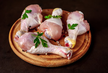 Chicken legs with spices, ready for cooking on a cutting board, background concrete