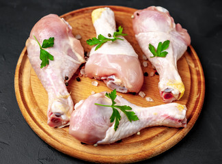 Chicken legs with spices, ready for cooking on a cutting board, background concrete