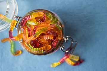 Chewing marmalade in the form of worms in a glass jar. Gummies.