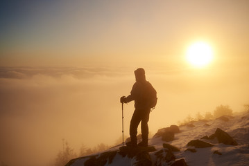 Back view of tourist hiker with backpack and hiking sticks resting on rocky mountain peak on copy...